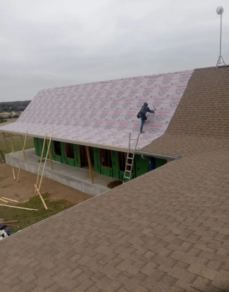 Worker preparing underlayment for a metal roof installation in Brent